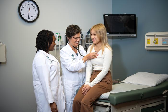 Two nursing professionals checking vitals of a patient